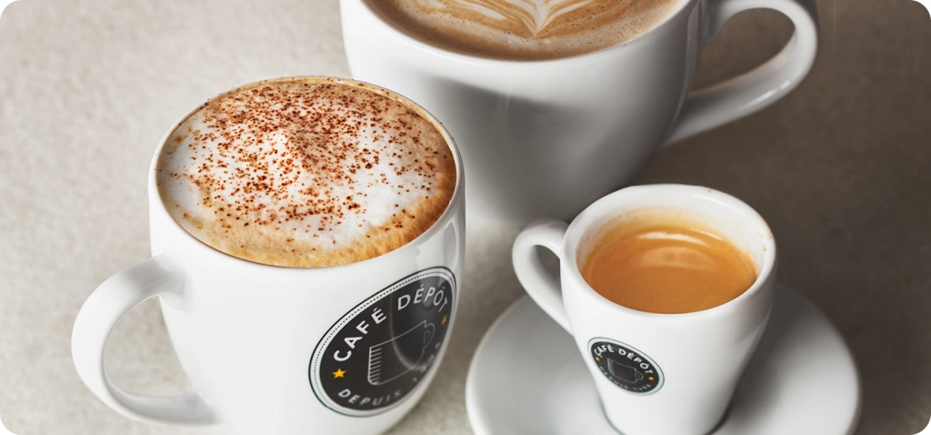 Three coffee cups, including a cappuccino and espresso, showcasing latte art.