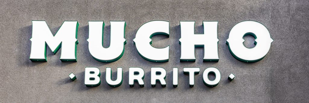 Signage for Mucho Burrito restaurant in bold, colorful lettering.