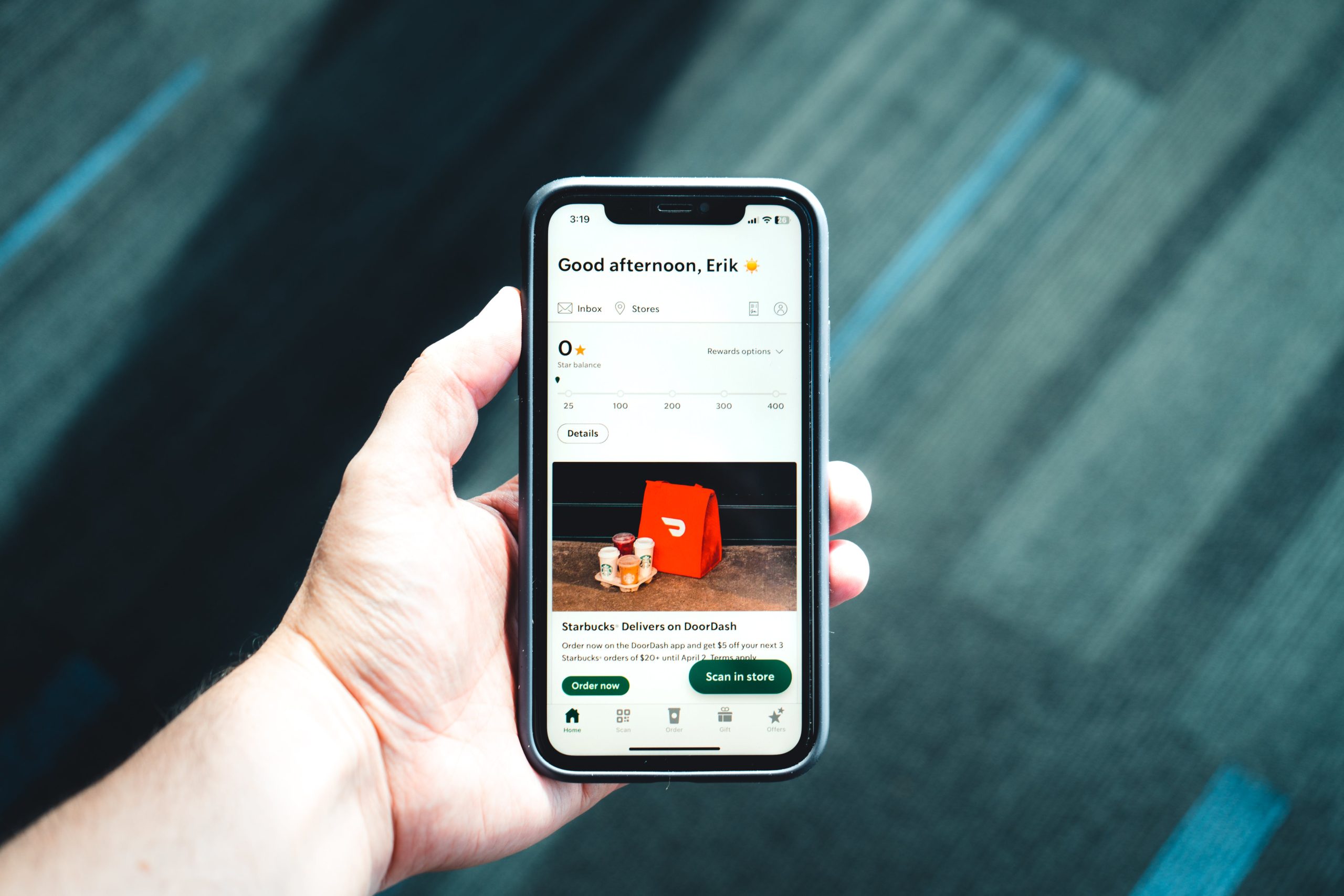 Hand holding a smartphone displaying a food delivery app interface with a Starbucks order.