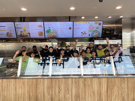 Franchise owner and team behind glass cabinets, smiling and raising their hands in victory | MTY Group Franchising Q&A: Your Questions Answered Blog