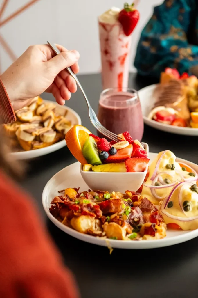 Allô mon Coco breakfast and brunch spread — fresh fruit, smoothies, and hearty plates, highlighting a family-friendly café and brunch franchise in Canada.