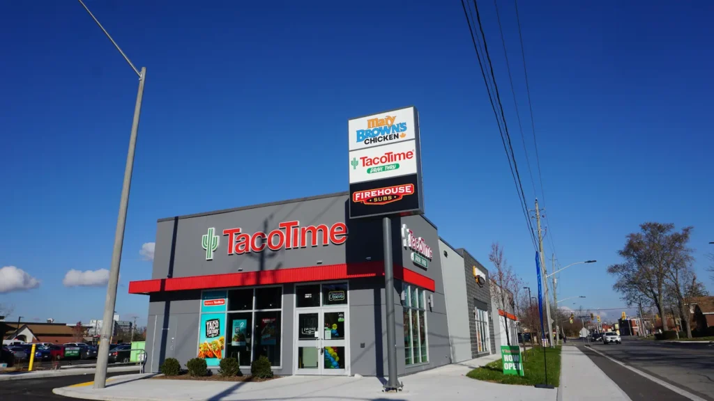 TacoTime restaurant exterior with drive-thru and multi-brand pylon sign showing Mary Brown's Chicken, TacoTime, and Firehouse Subs.